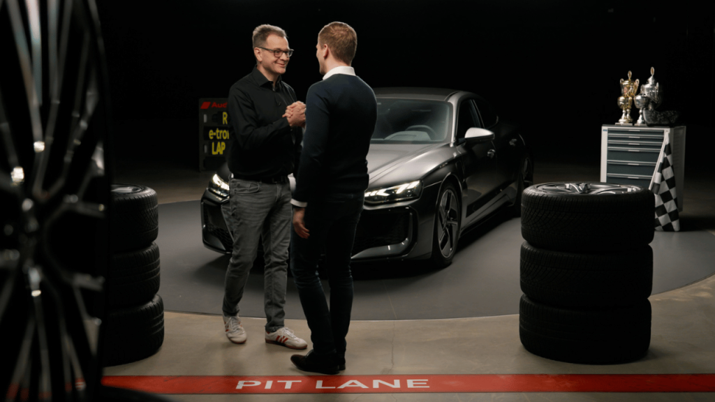 Zwei Moderatoren vor dem Audi e-tron GT im Boxen-Set