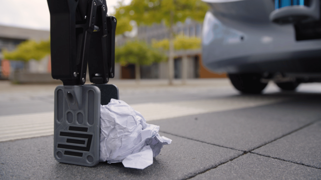 Greifarm des EDAG CityBot hebt Papiermüll auf